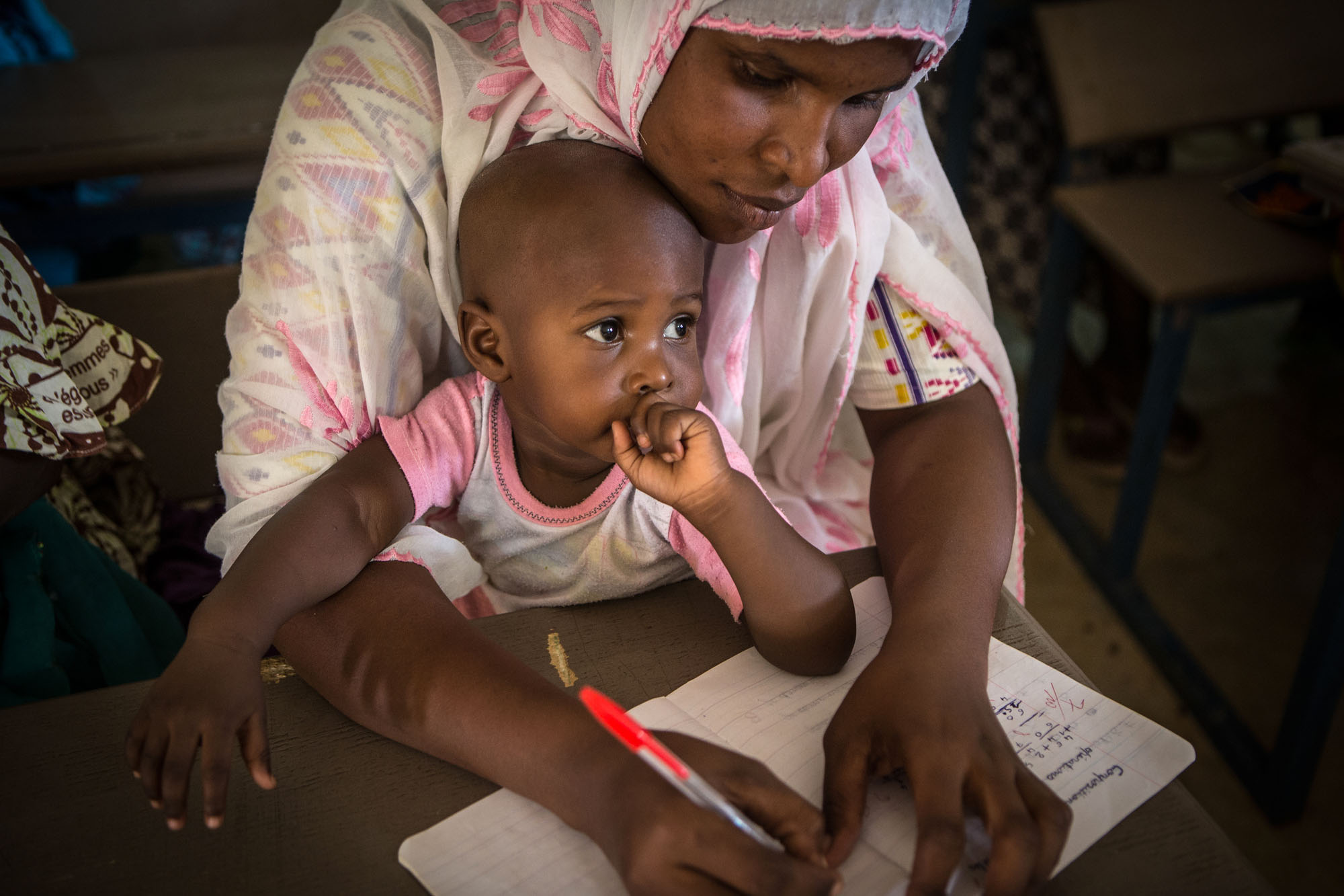 An adult and a child in a classroom or community space.