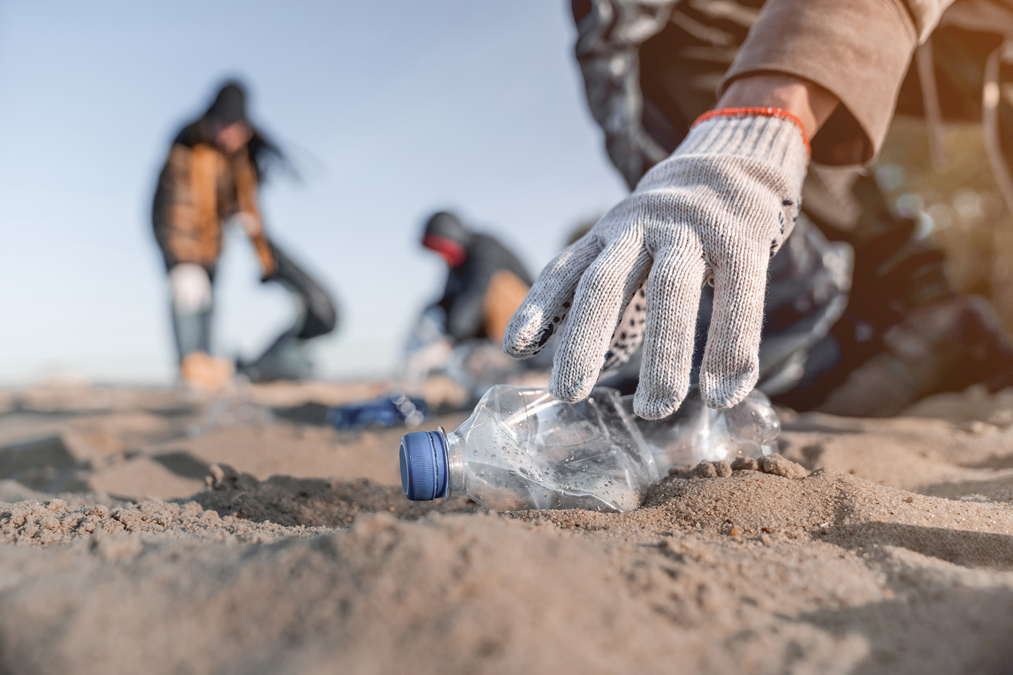 closeup of hands picking up beach litter