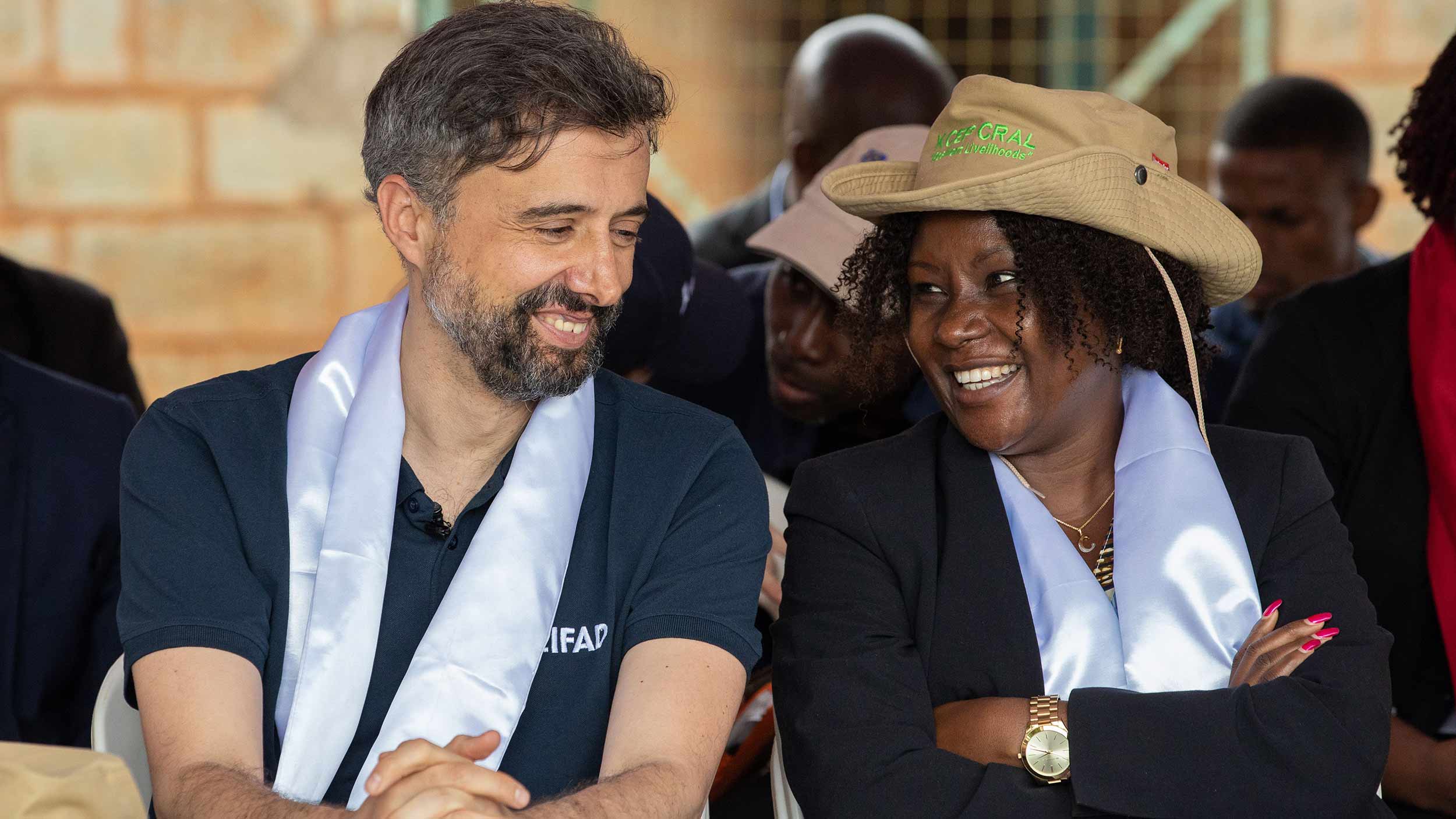 Alvaro is smiling together with a woman. They are seated next to each other among a crowd.