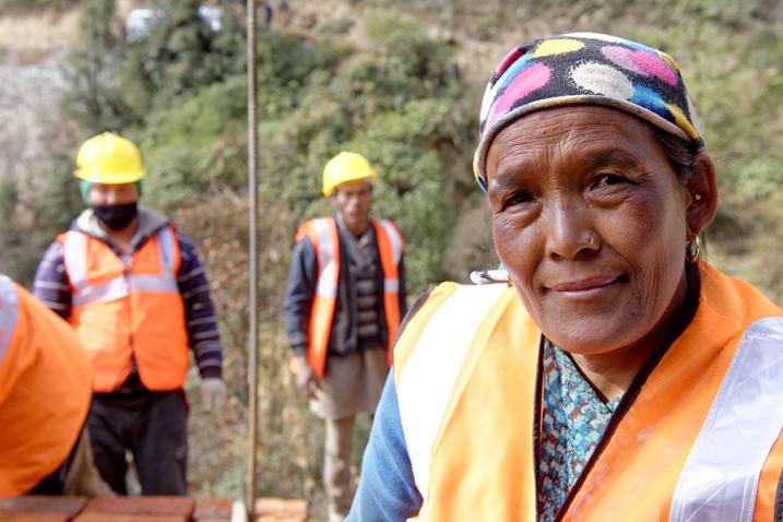 Pay equity is about fairness in pay, women and men should receive equal remuneration for the same work or work of equal value. Portrait of a woman with men in the background.