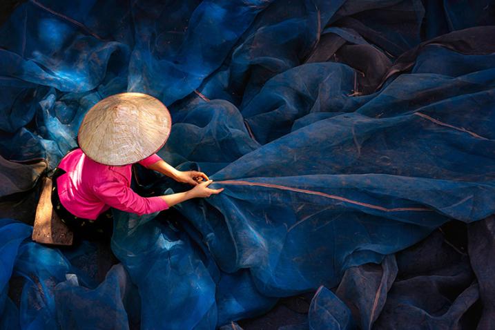 figure with straw hat holding fishing nets seen from above