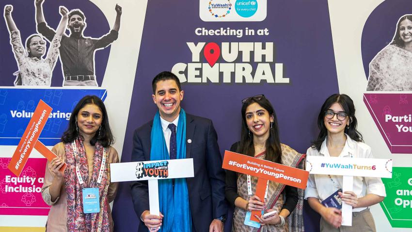 Felipe in a photo-op with 3 young women. They are holding signs with hashtag key messages.