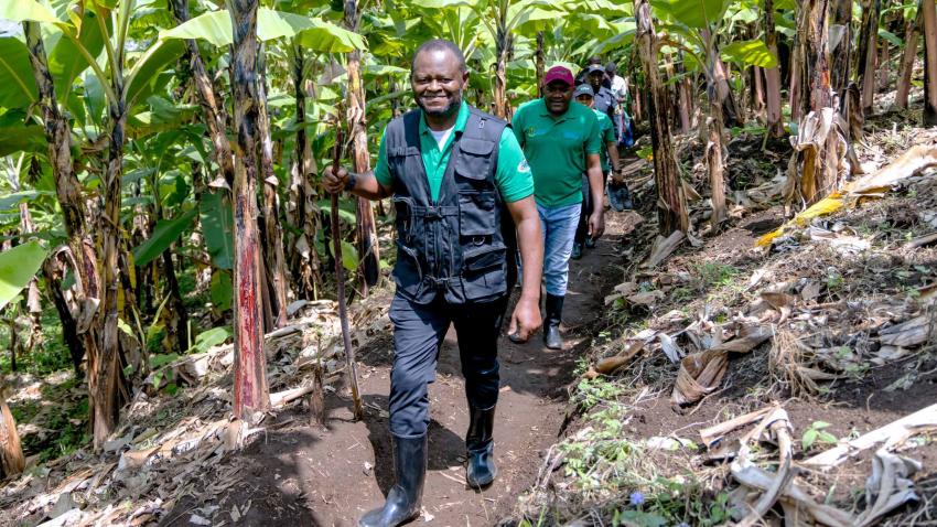 Ozonnia walks along a narrow pathway in a forest with people following behind