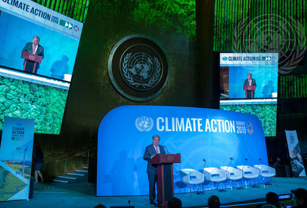 A photograph of a farm field lined by windmills