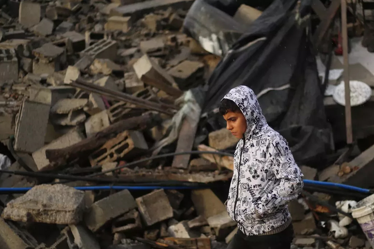 A photograph showing a young person walking through the wreckage of an exploded building